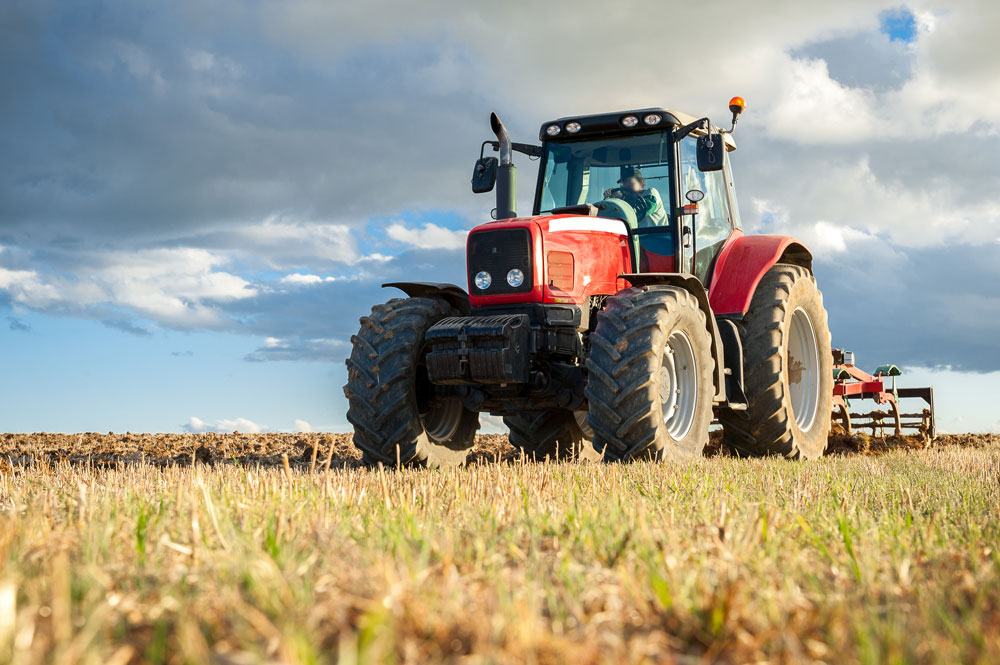 Bild zeigt einen roten Traktor, der sich in der Mitte eines Feldes befindet.
