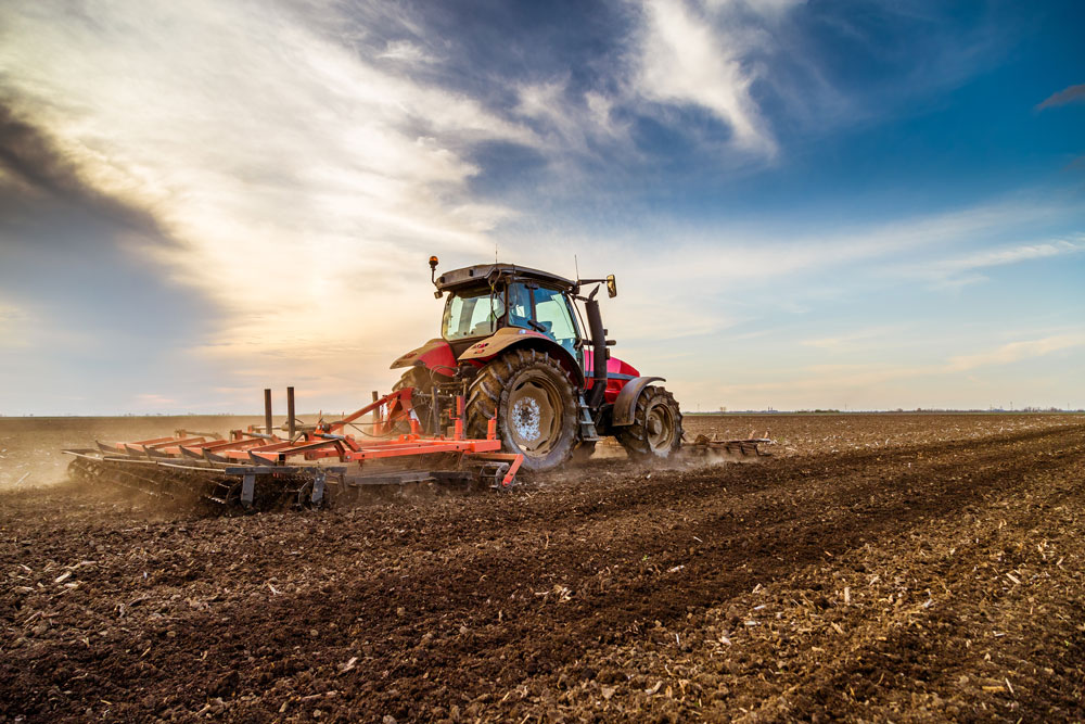 Bild zeigt einen Traktor auf einem Feld beim Pflügen, welches Huminstoffe in der Landwirtschafts spiegelt